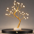 36-LED bonsai tree lamp with warm white lights, golden branches and a white base, shown on a black display platform