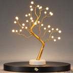 36-LED bonsai tree lamp with warm white lights, golden branches and a white base, shown on a black display platform